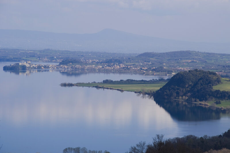 Il promontorio di Bisenzio nel lago di Bolsena e sullo sfondo il borgo di Capodimonte.